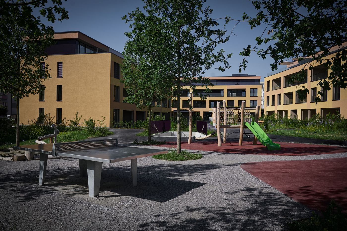 Der Quartierplatz zwischen den Häusern mit Spielgeräten, Sitzbank und jungen Bäumen.